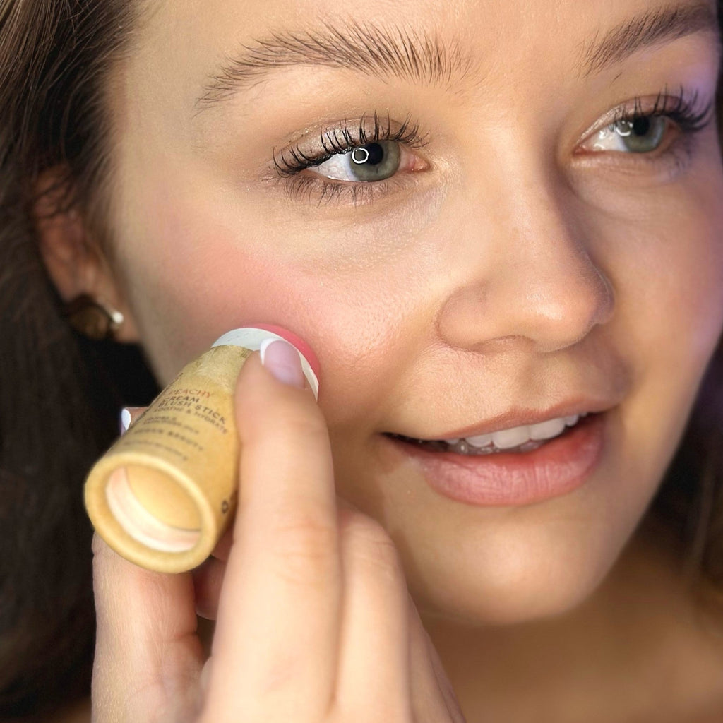 Woman applying blush in a paper tube to her face