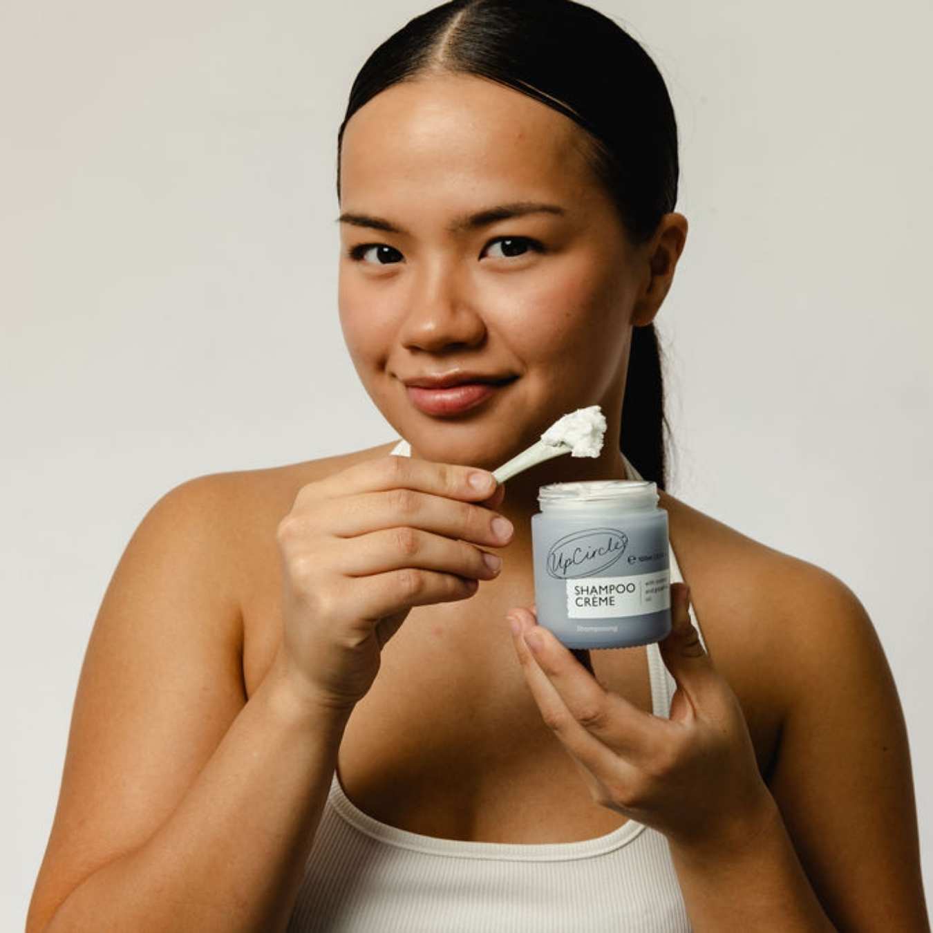 Woman holding a jar of shampoo crème with a scoop