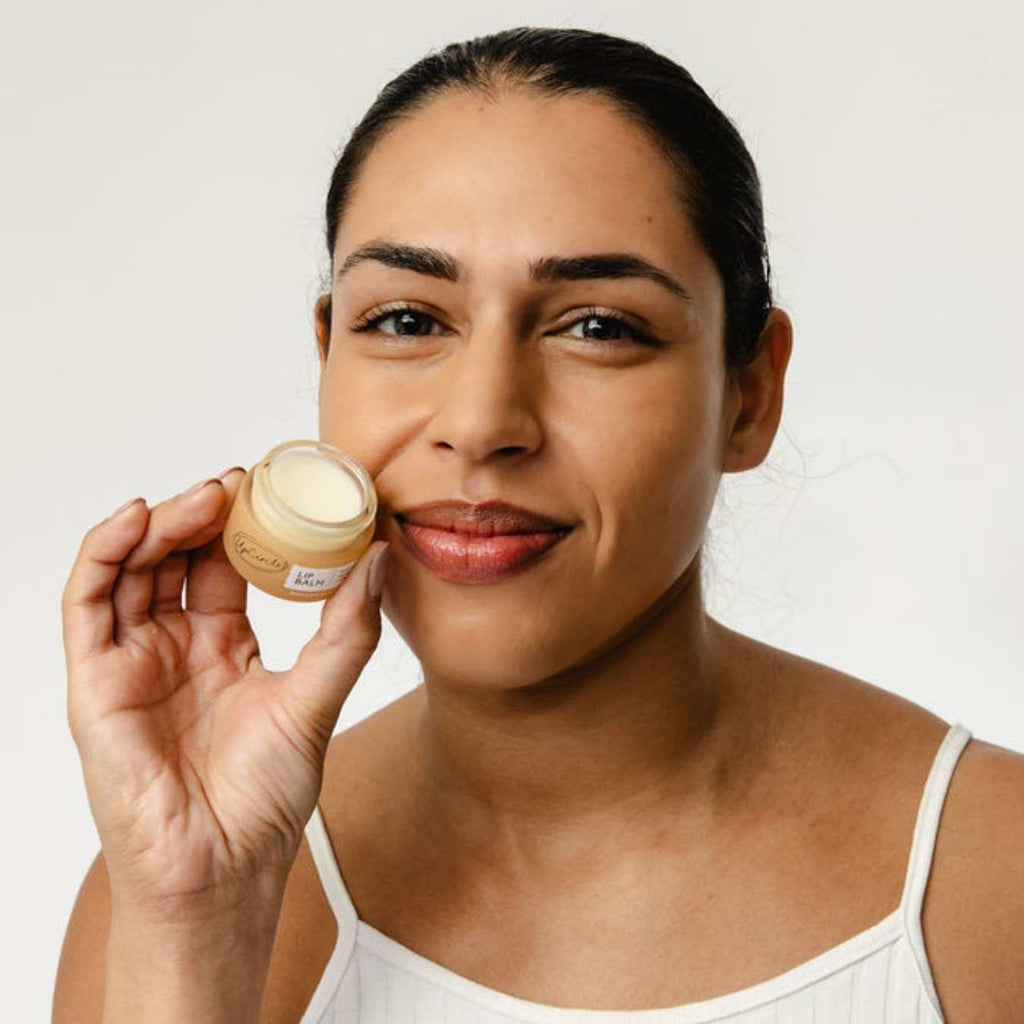 Woman holding a jar of lip balm against a white background