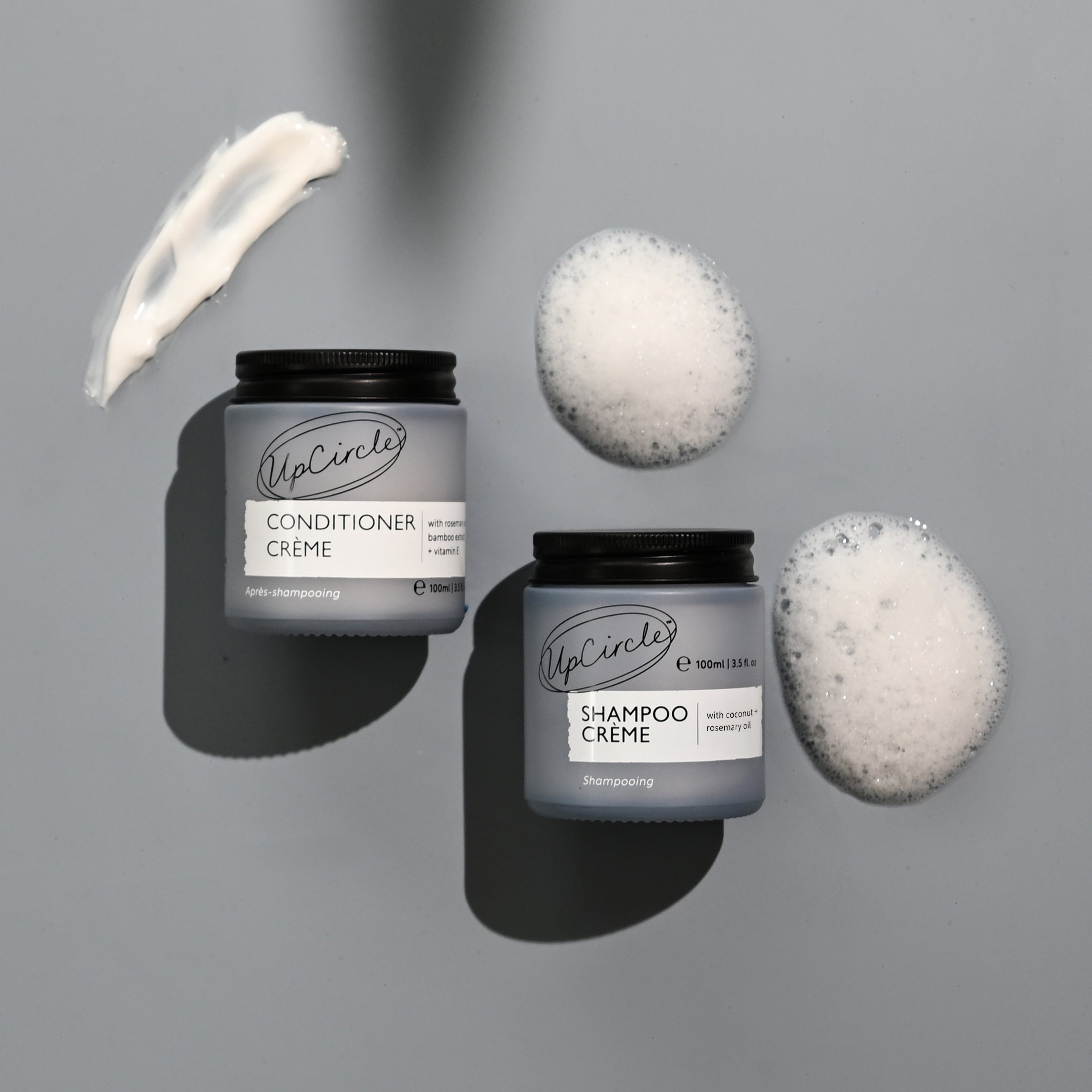 UpCircle conditioner and shampoo crème with product application on a gray background