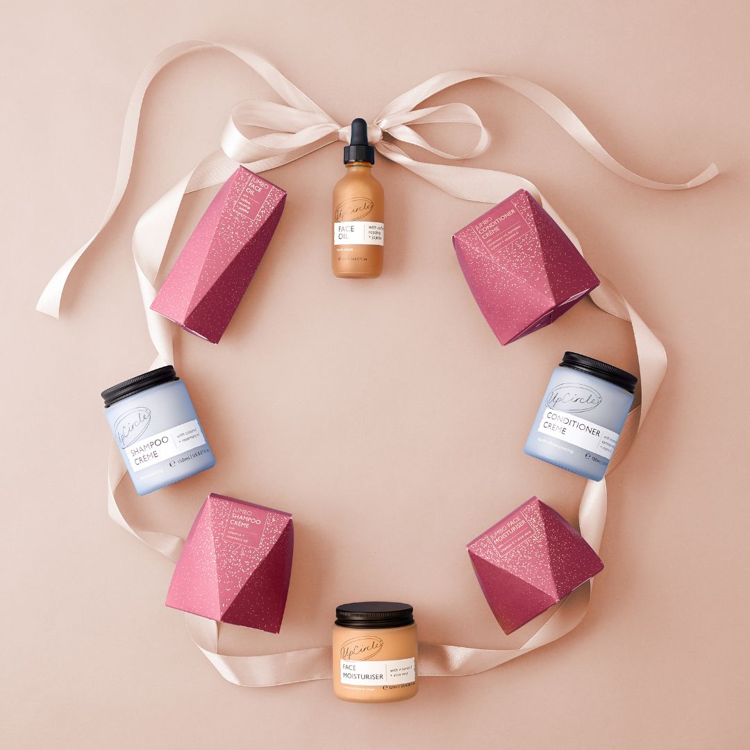 Cosmetic products including bottles and boxes arranged on a pink background with ribbons.
