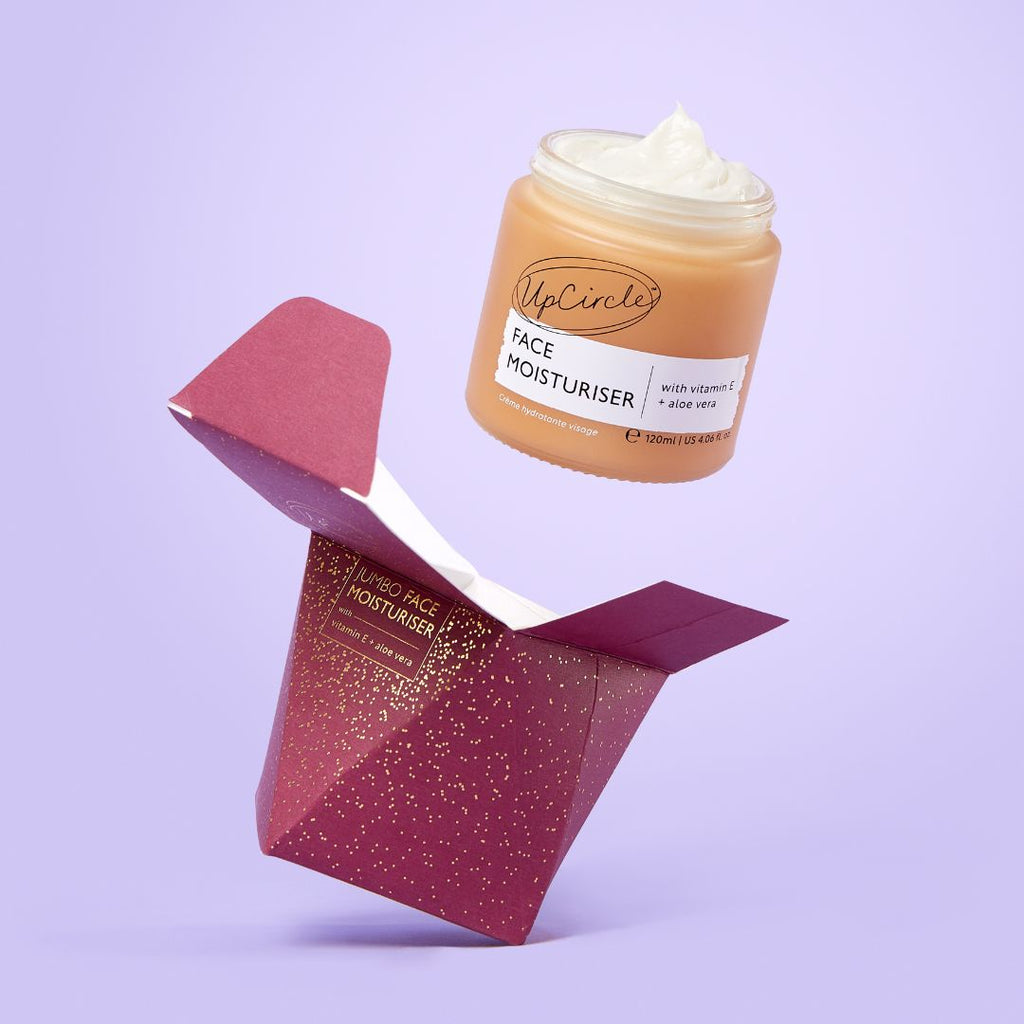 UpCircle face moisturizer jar with open red packaging on a light purple background