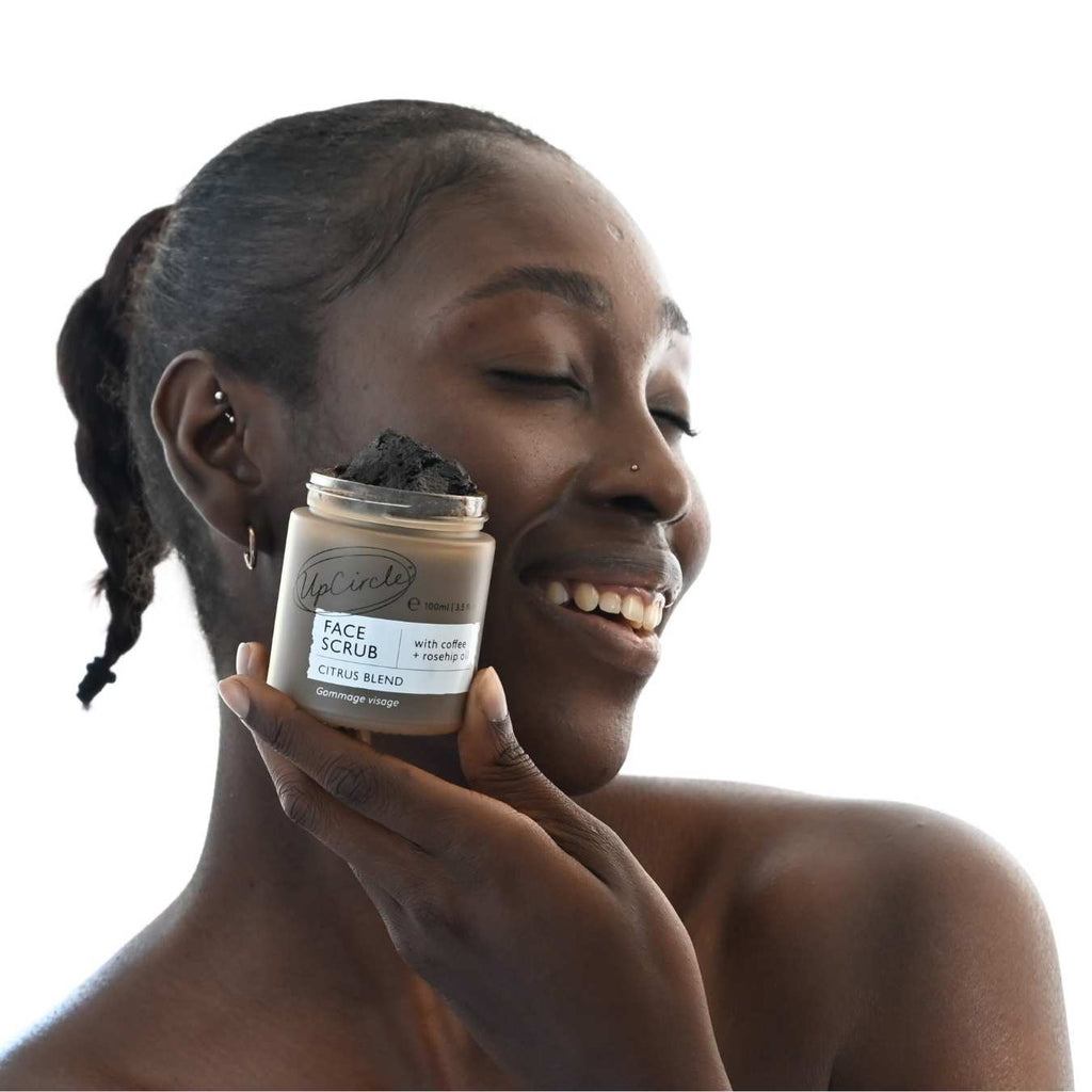 Woman holding a jar of face scrub with a neutral background