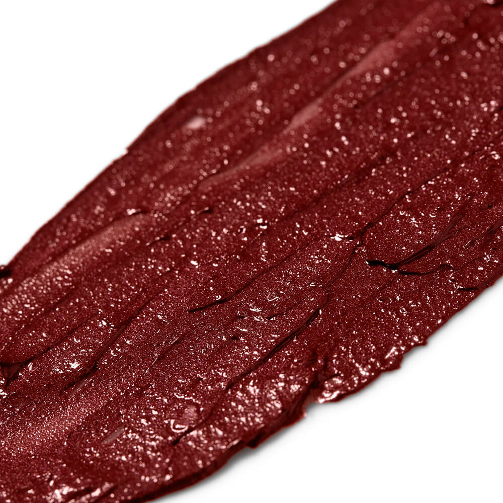 Close-up of a swatch of dark red glittery lip gloss on a white background