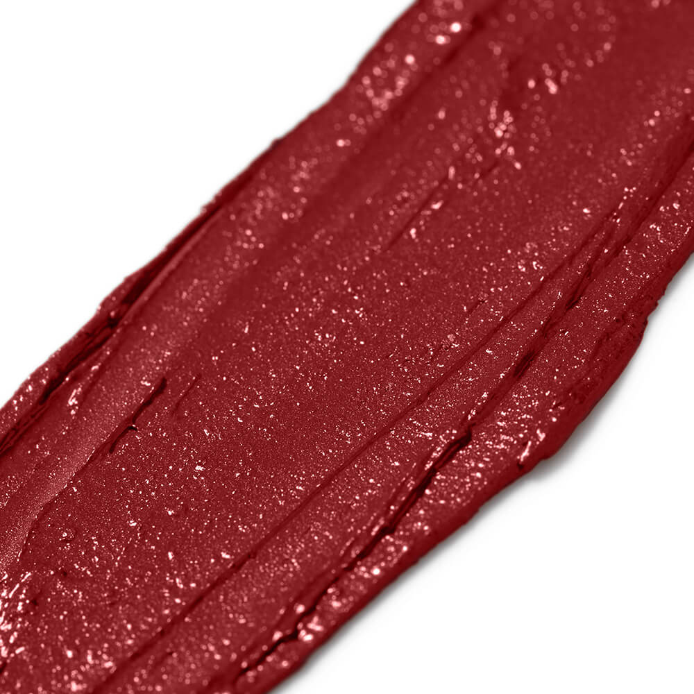 Close-up of a swatch of red glittery makeup on a white background