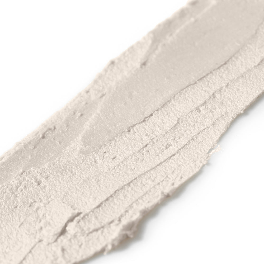 Close-up of a textured white makeup swatch on a light gray background