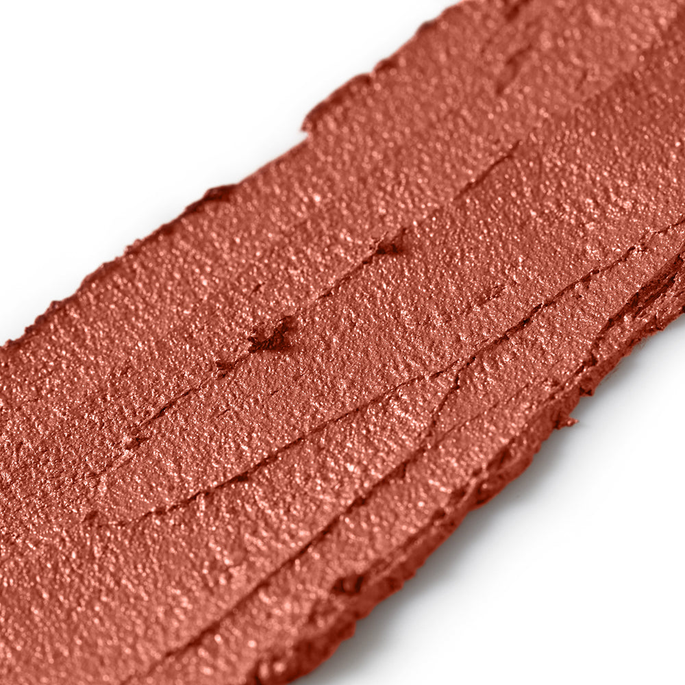 Close-up of a bronze-colored makeup swatch on a white background