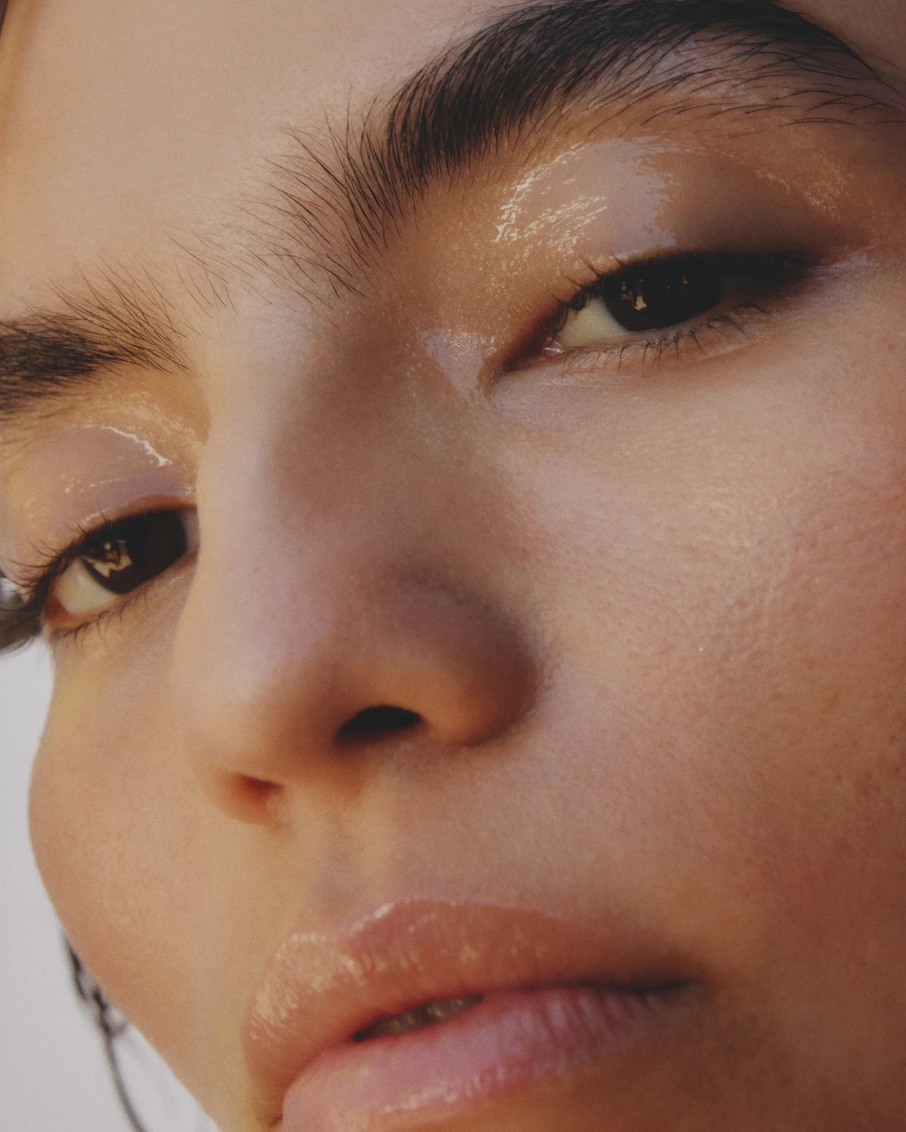 Close-up of a person's face wearing glossy makeup with a neutral expression