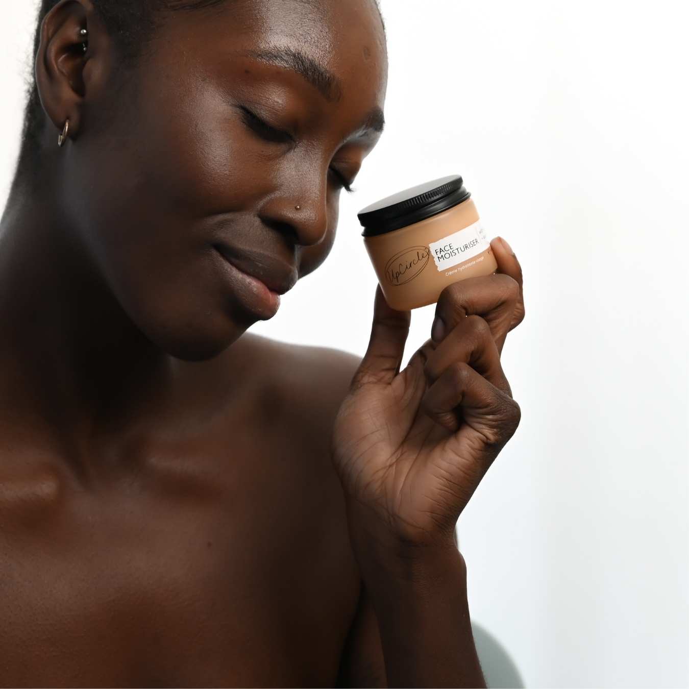 Woman holding a jar of skin product with a neutral background