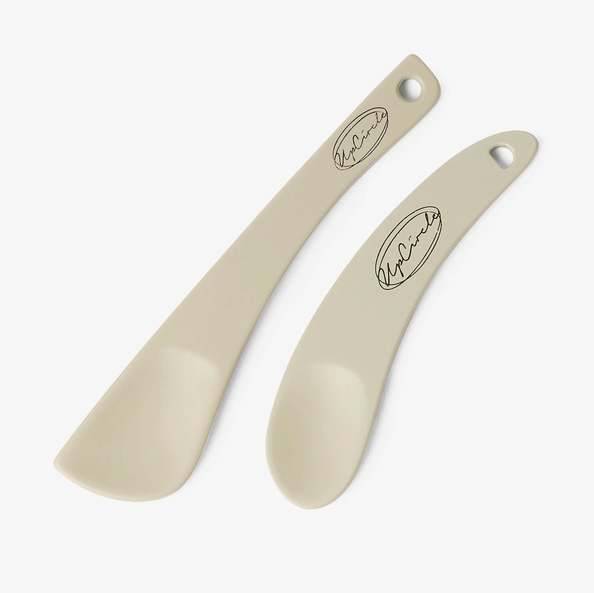 Two beige cosmetic spatulas with a brand logo on a white background
