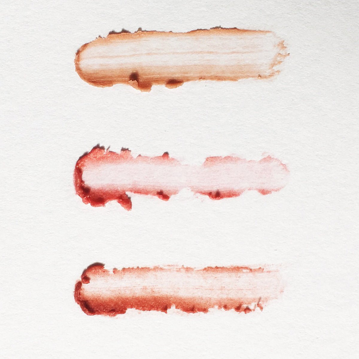 Three cosmetic swatches on a white background