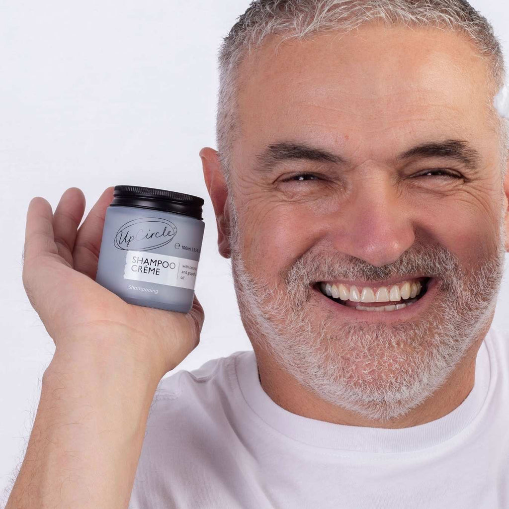 Man holding a container of UpCircle shampoo crème with a white background