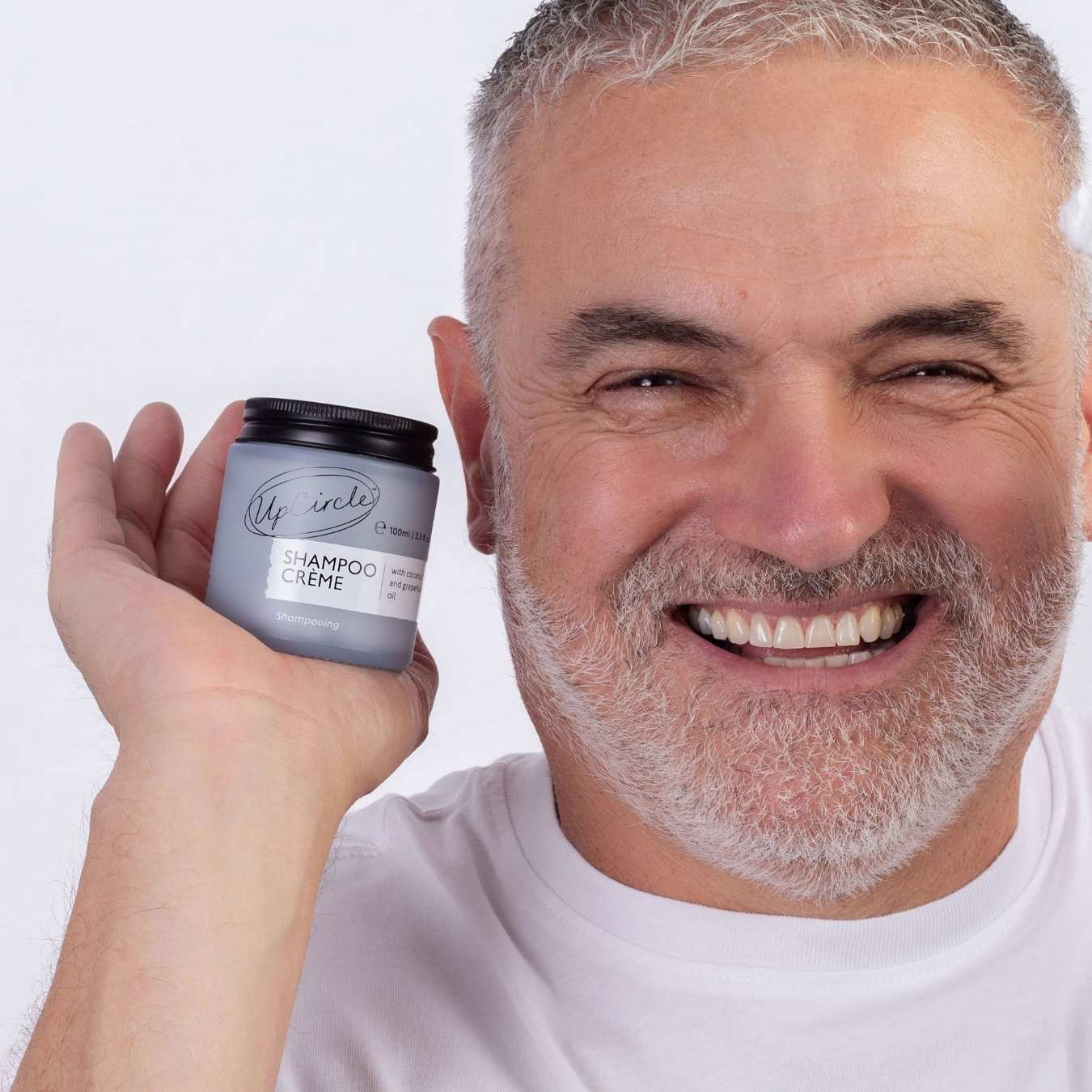 Man holding a container of UpCircle shampoo crème with a white background