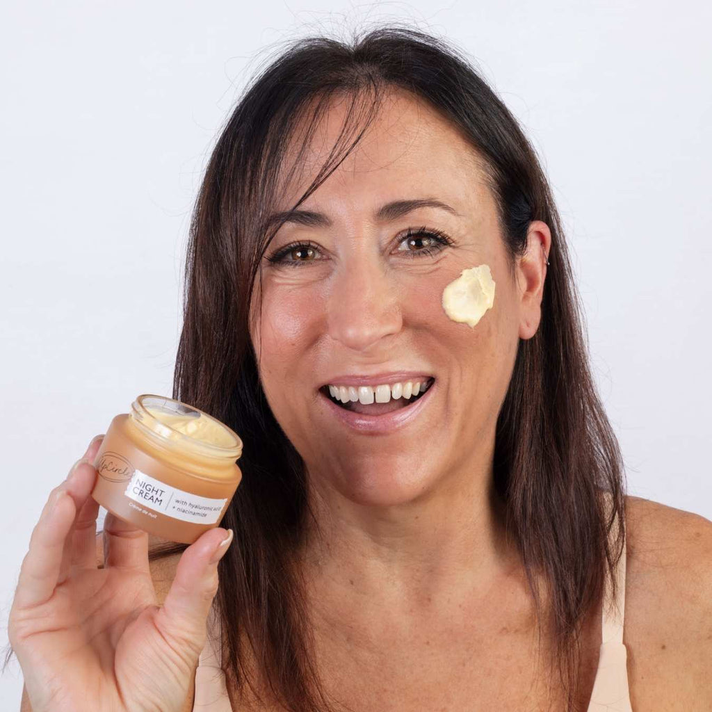Woman applying cream to her face with a jar of the same cream.