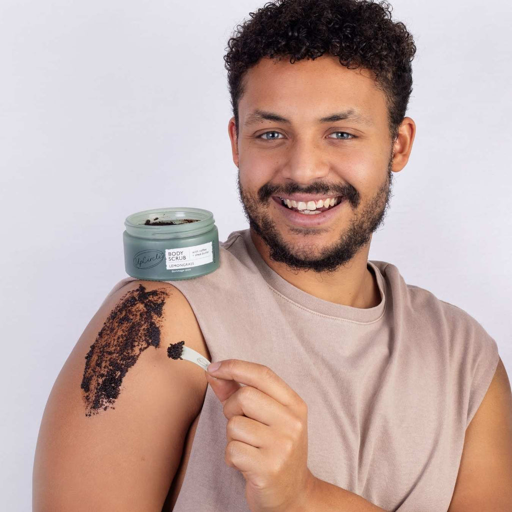 Man applying a scrub to his arm with a jar of scrub in the background