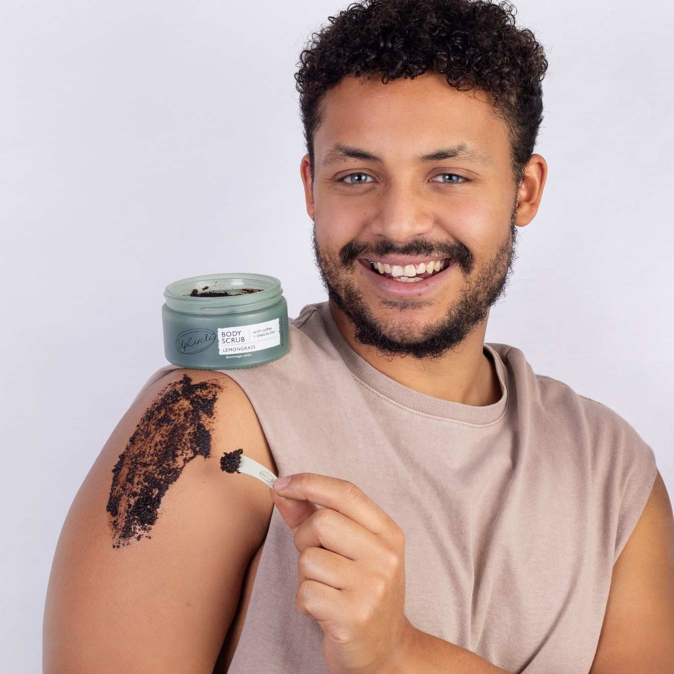 Man applying a scrub to his arm with a jar of scrub in the background