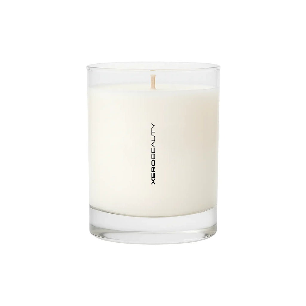 White candle in a glass container with 'Xerobeauty' branding on a white background