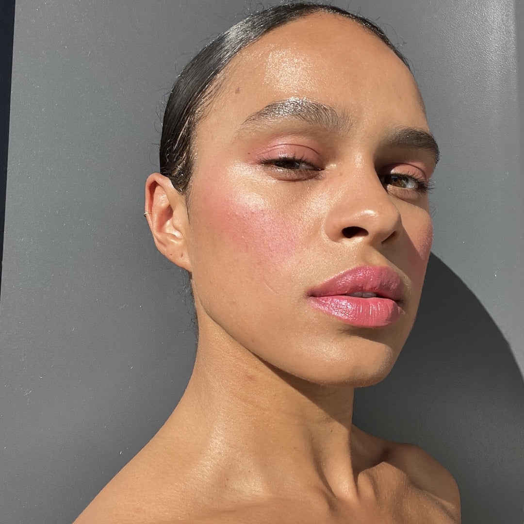 Woman with a neutral expression wearing makeup against a gray background