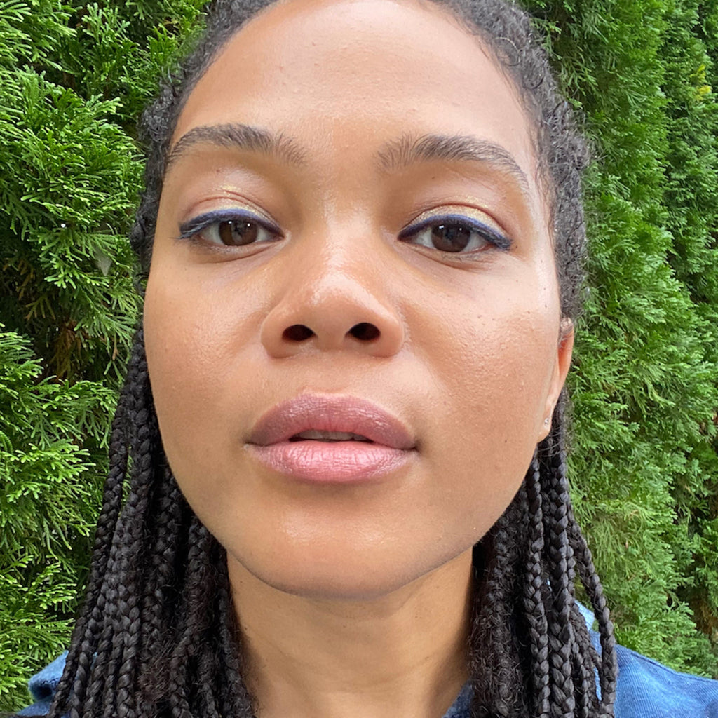 Woman with braided hair in front of green foliage