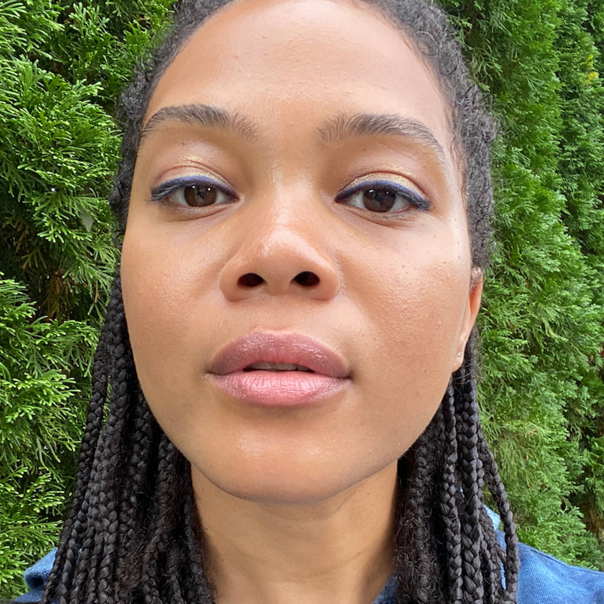 Woman with braided hair in front of green foliage