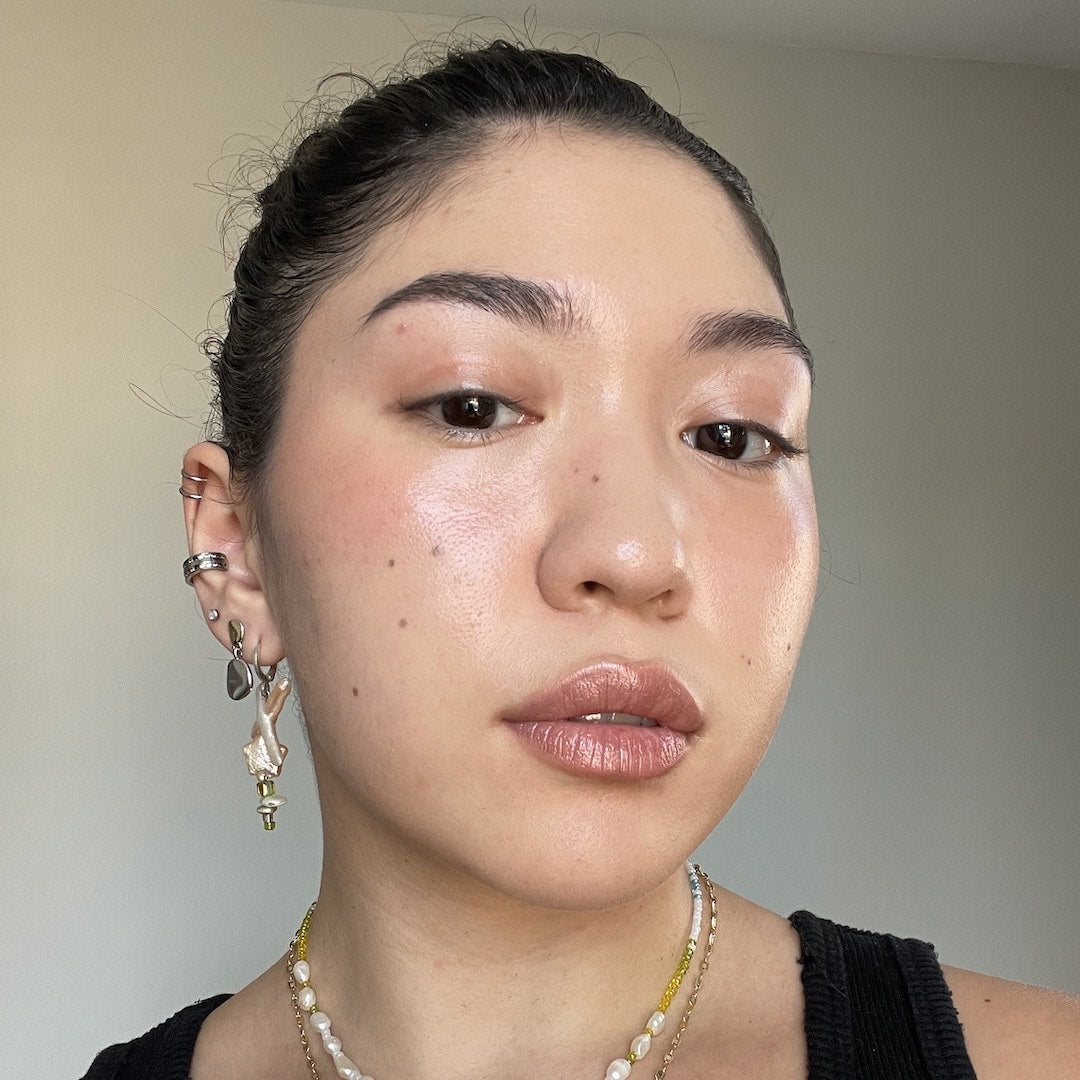 Close-up of a person with earrings and a necklace against a neutral background