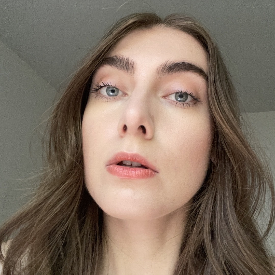 Close-up of a person with long brown hair against a neutral background