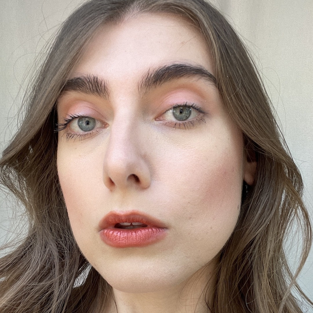 Close-up of a person with light makeup against a neutral background