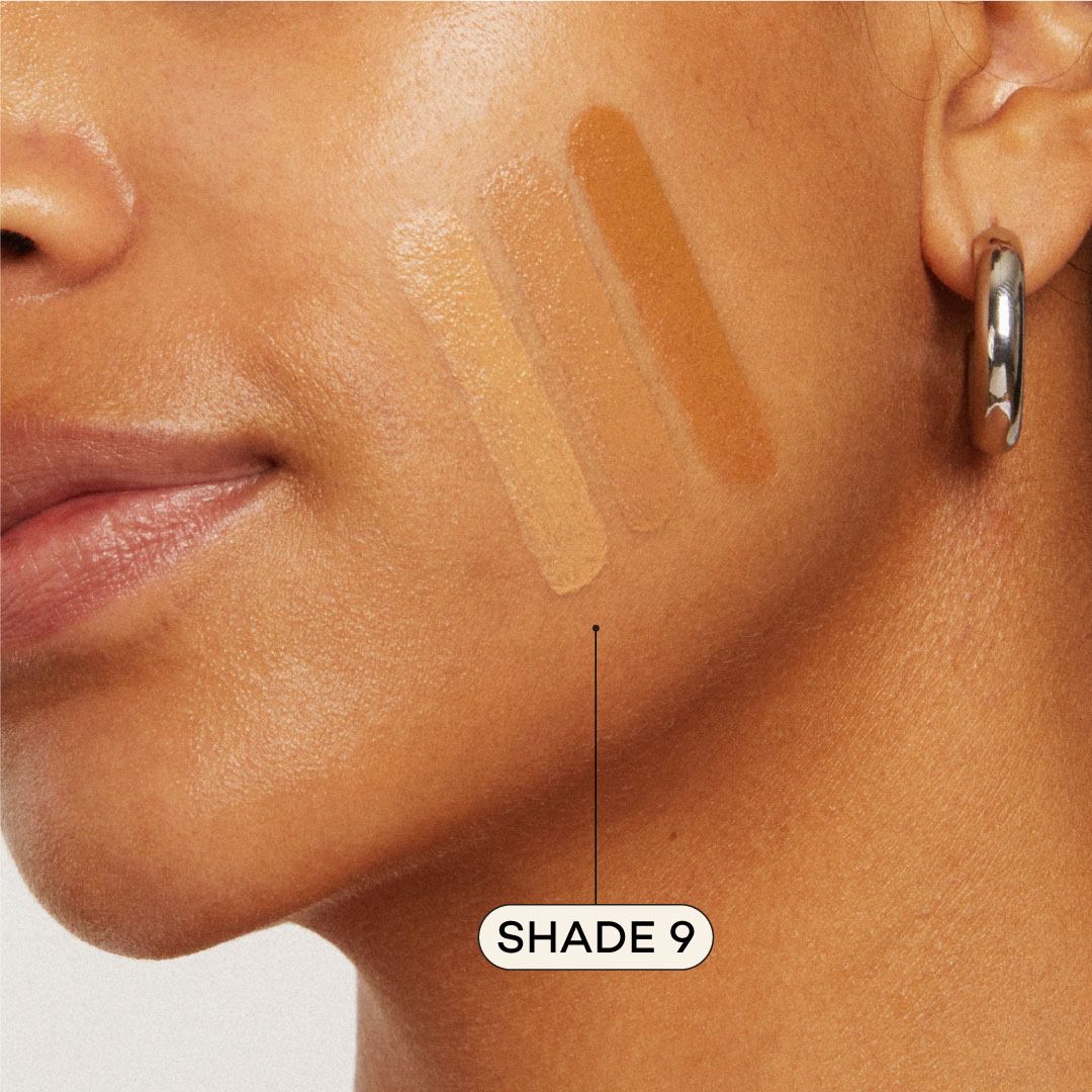 Close-up of a person's cheek labeled 'Shade 9' with three swatches of foundation applied.