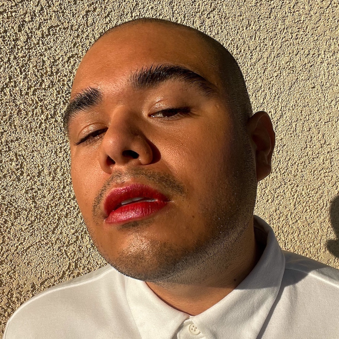 Man wearing red lipstick against a beige wall