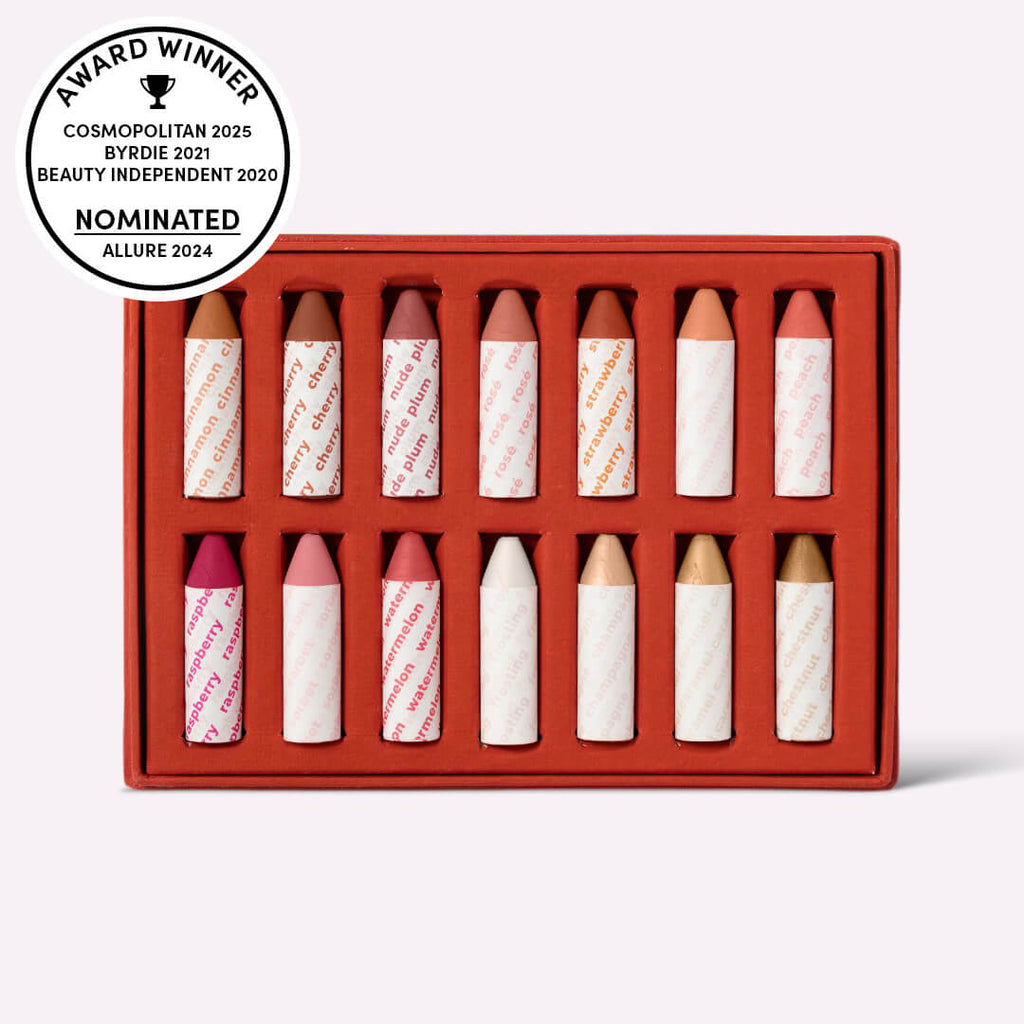 Set of lip crayons in a red box with awards on a white background