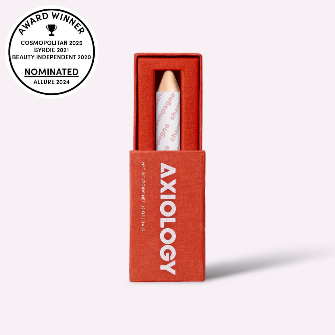 Axiology makeup crayon in a red box with award nominations on a white background