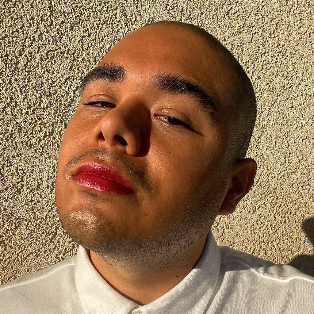 Man wearing makeup against a textured beige wall