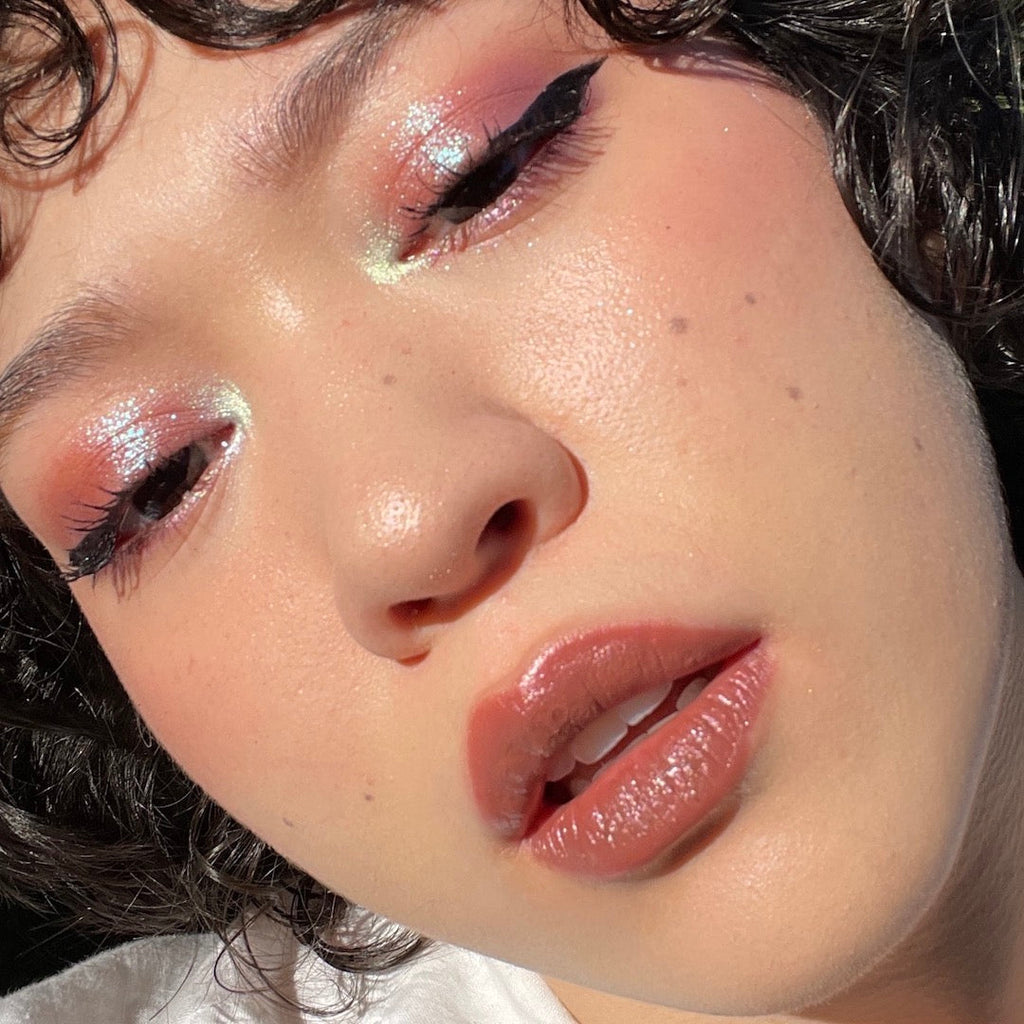 Close-up of a person with glittery eye makeup and pink lip color.