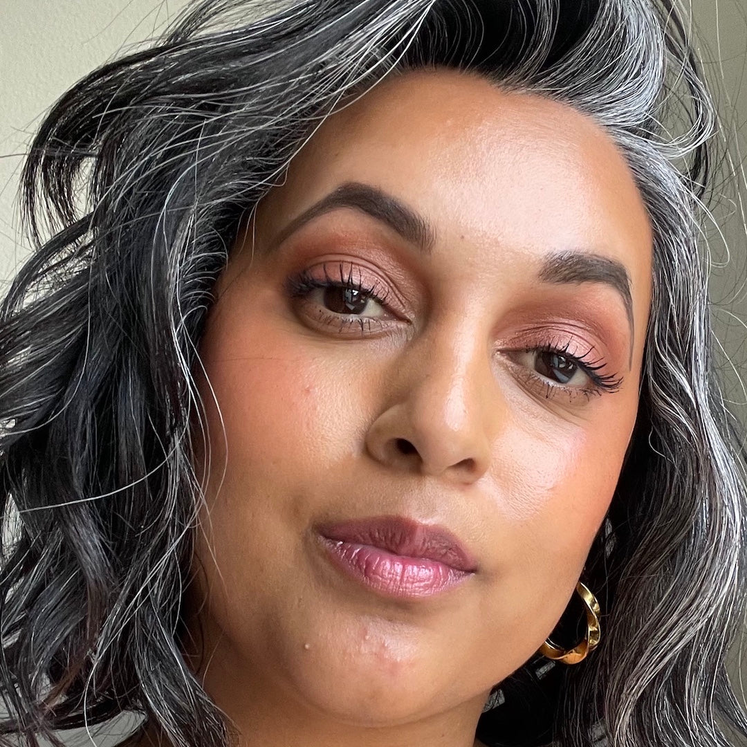 Close-up of a person with gray hair and pink makeup