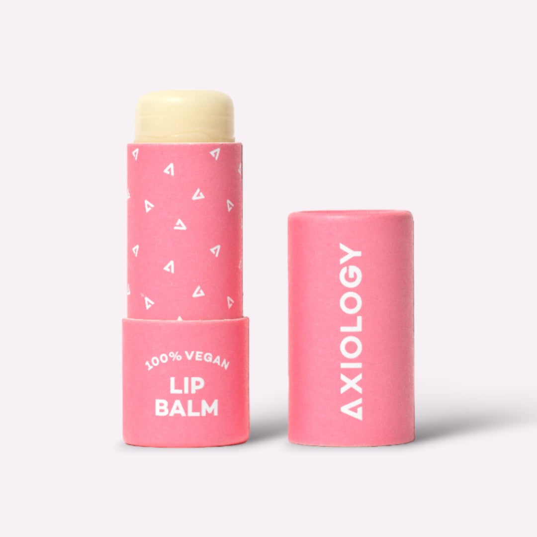 Pink lip balm tube with cap on a light gray background