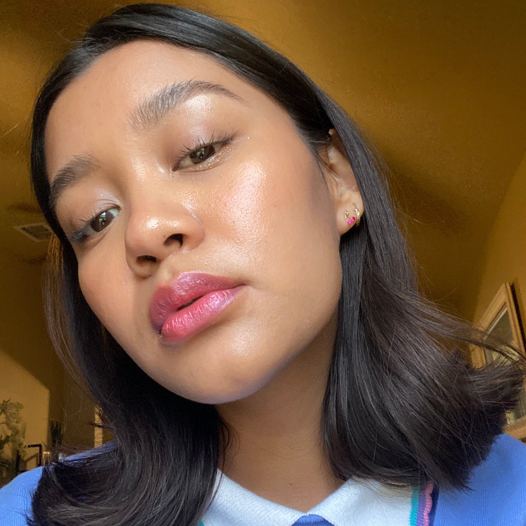 Close-up of a person with dark hair and pink lipstick indoors.
