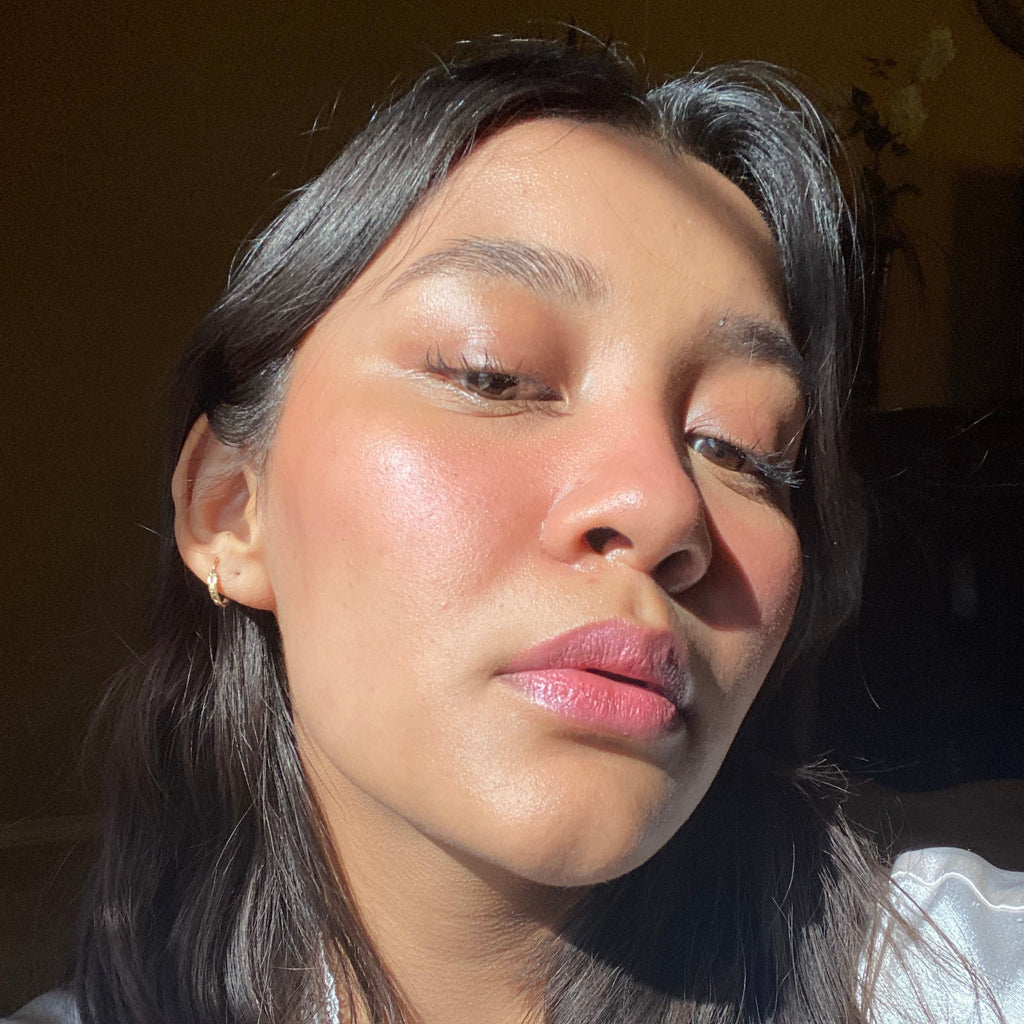 Close-up of a person with dark hair and pink lipstick against a blurred background