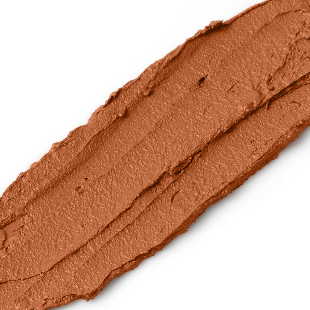 Close-up of a swatch of 'cinnamon' brown makeup cream on a white background