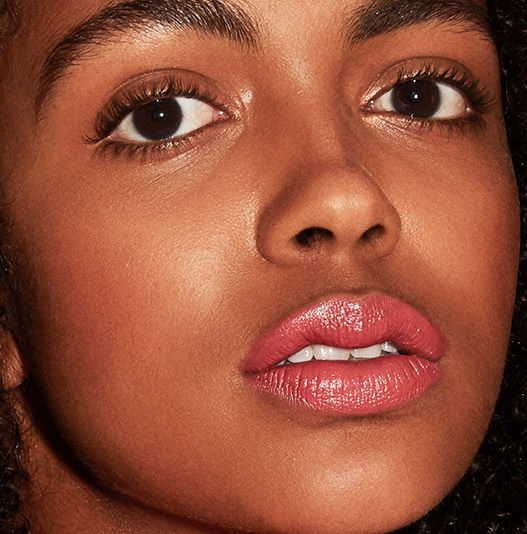 Close-up of a woman's face with pink lipstick on a dark background