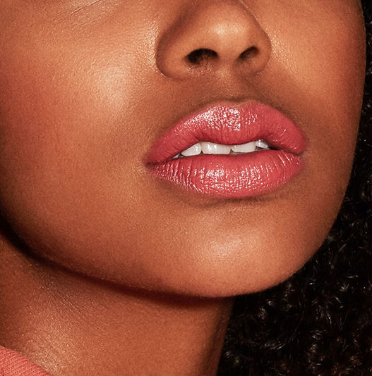 Close-up of a person wearing pink lipstick with a blurred background