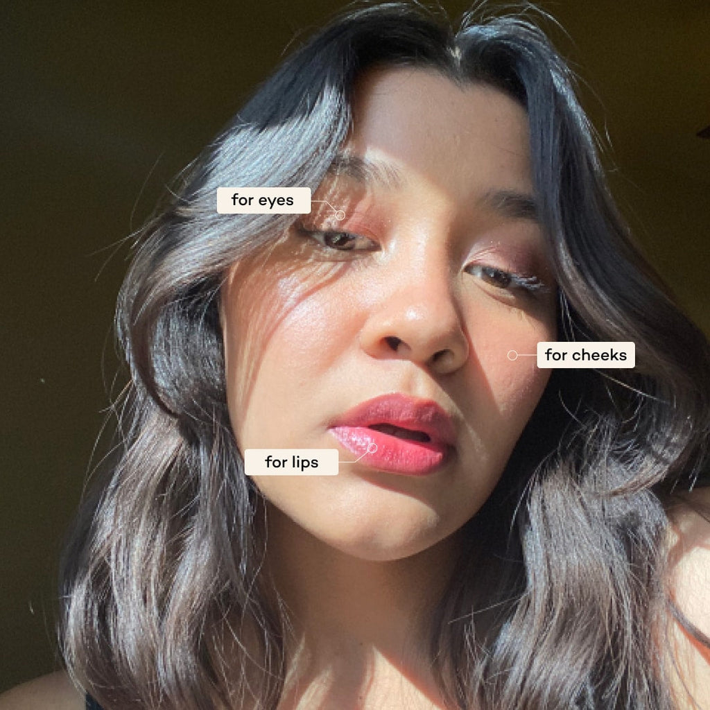 Woman with makeup labeled for eyes, cheeks, and lips against a dark background