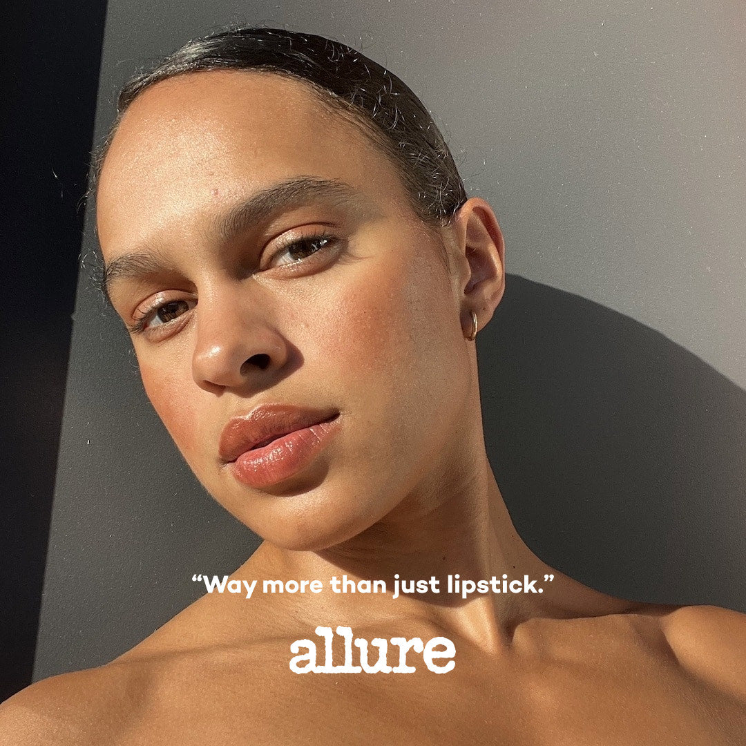 Woman with minimal makeup against a gray background, featuring the 'allure' brand.