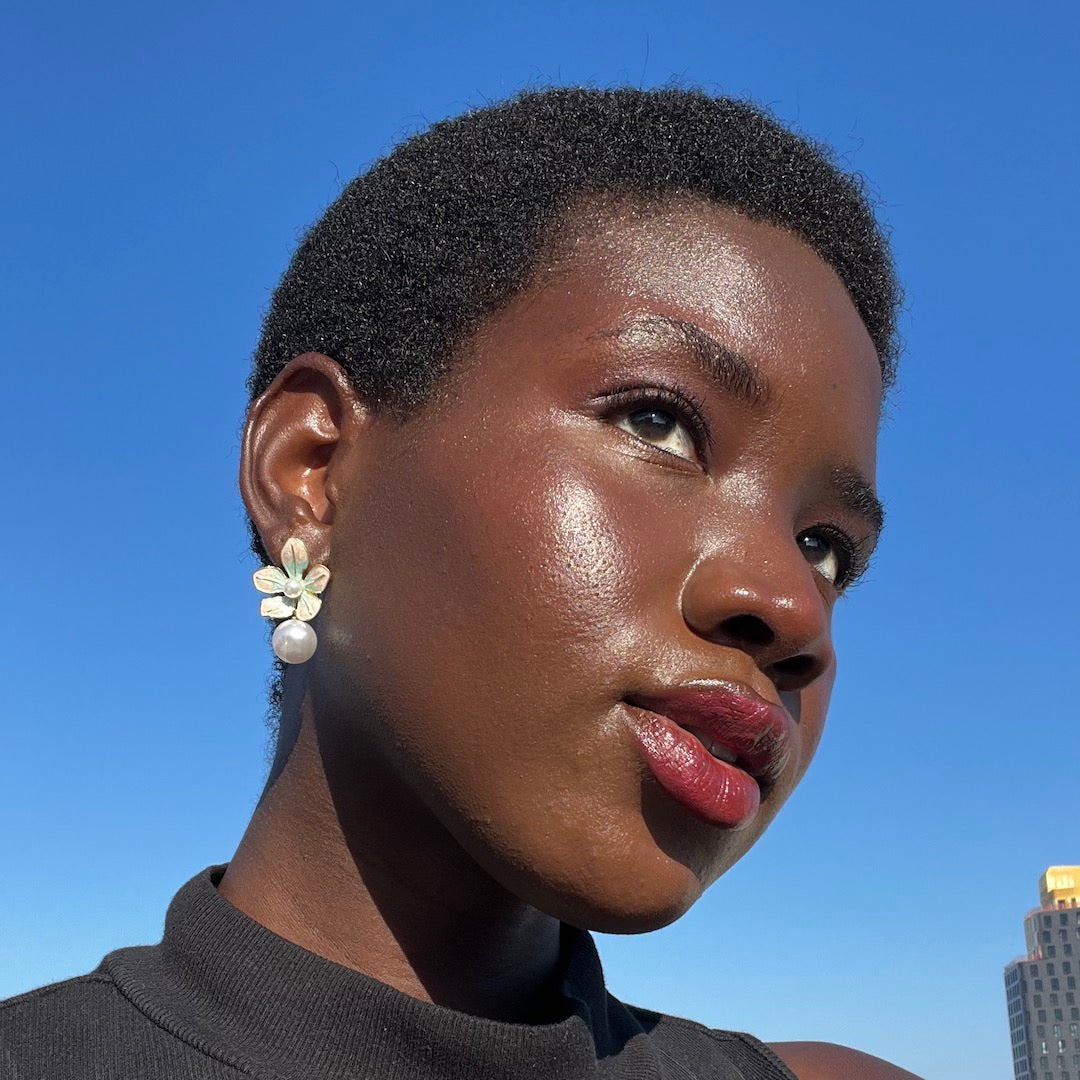 Woman with a short haircut and floral earrings against a clear blue sky