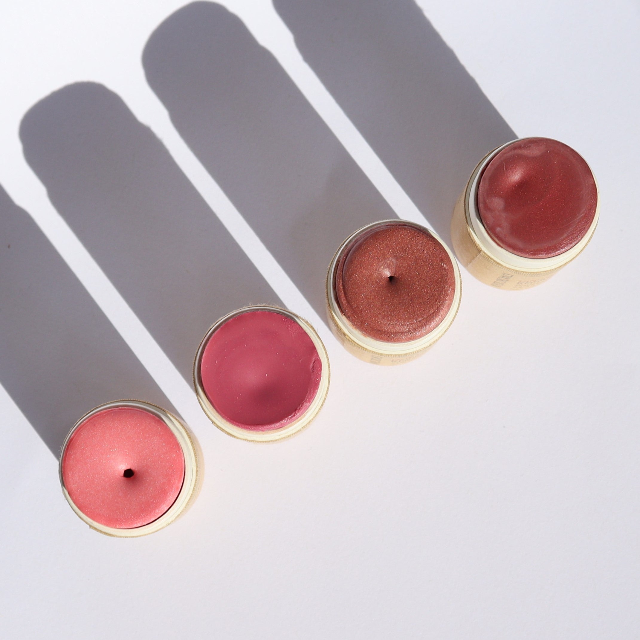 Four blush sticks in different shades on a white background