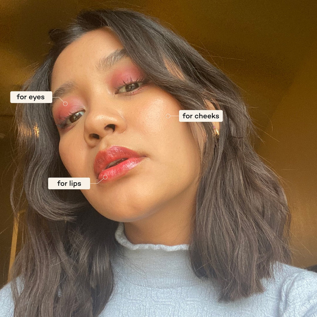 Woman with makeup labeled for eyes, cheeks, and lips against a warm-toned background