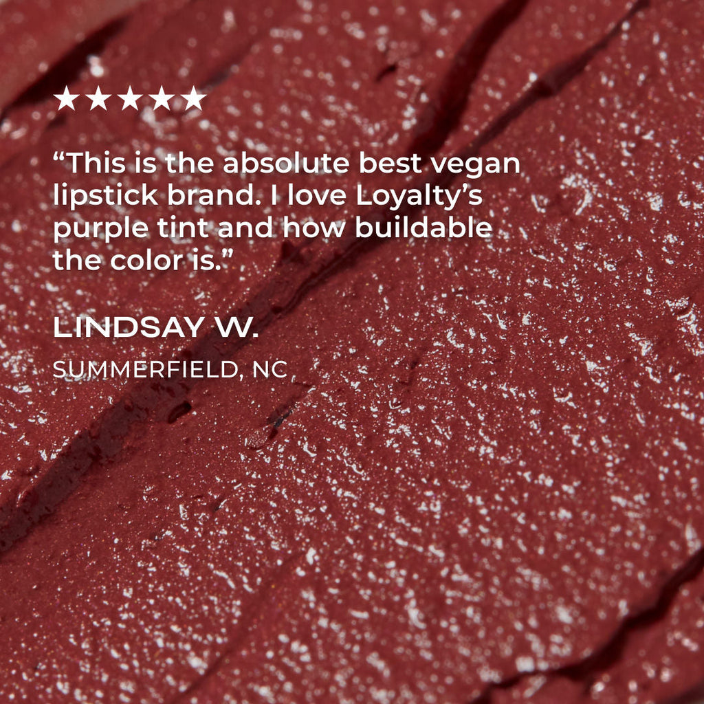Close-up of a rosey lipstick with a review quote on a red background
