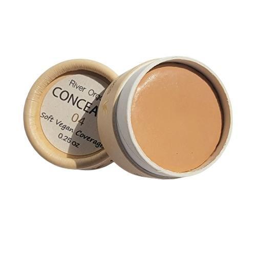Open container of concealer with visible product inside on a white background