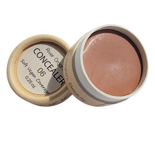 Open container of concealer with visible product inside on a white background