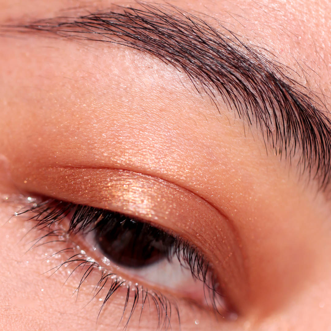 Close-up of a person's eye with brown eyeshadow and eyelashes.
