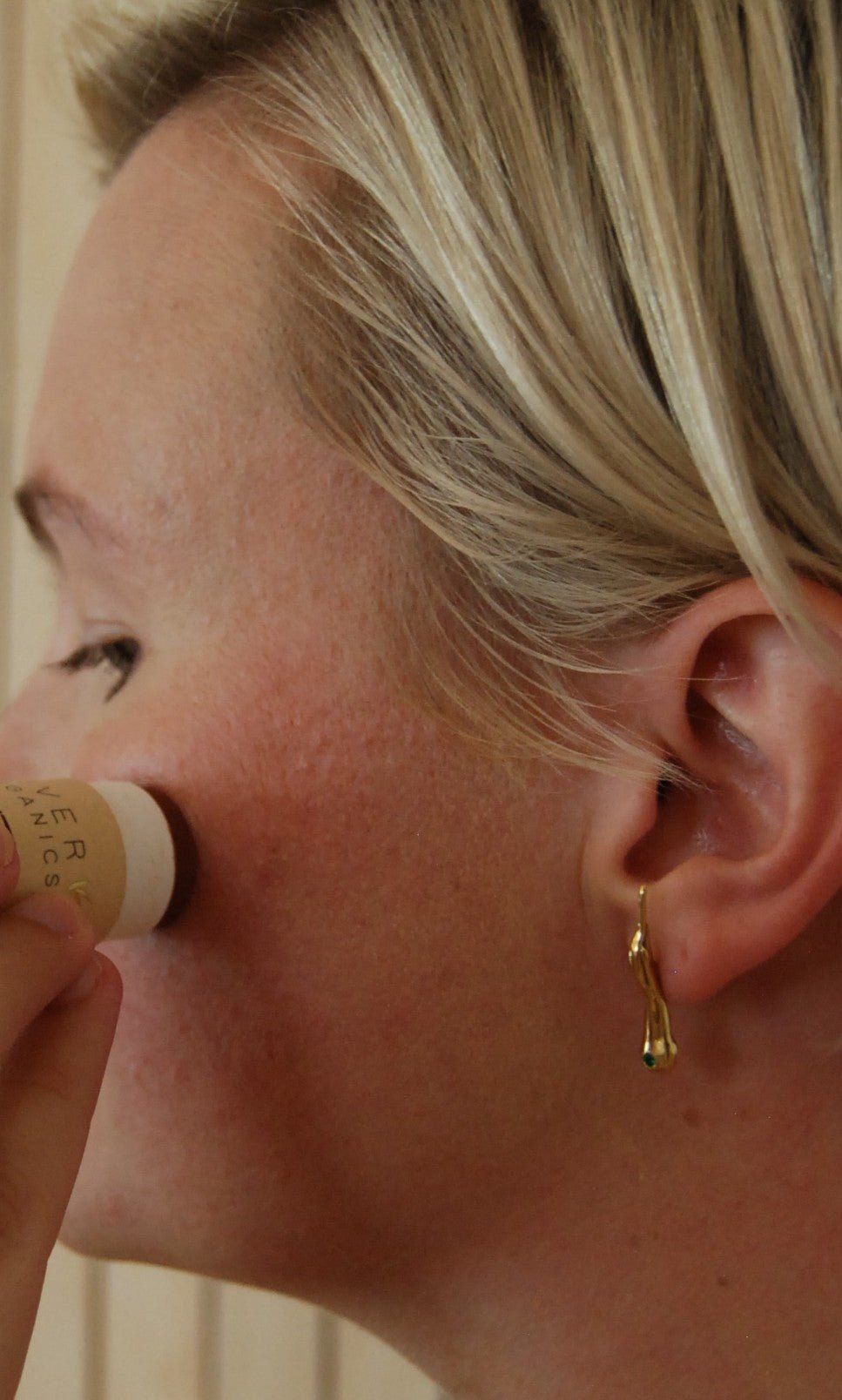 Close-up of a woman applying bronzer stick to cheek bone